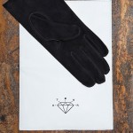 a suede glove designed by Maison Fabre for Otzar held in a white soft leather pouch.